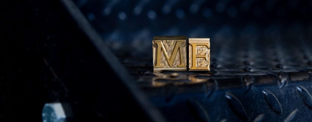 Brass type spelling "ME" sat on black metal stairs